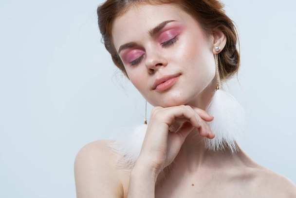 attractive woman bare shoulders fluffy earrings cosmetics close-up - Foto, afbeelding