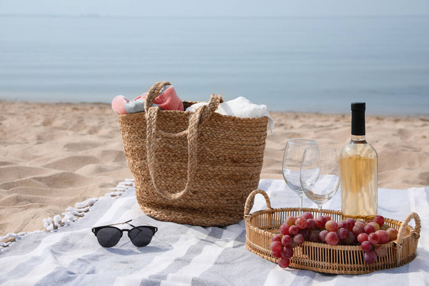 Bag, blanket, wine and other stuff for beach picnic on sandy seashore - Φωτογραφία, εικόνα