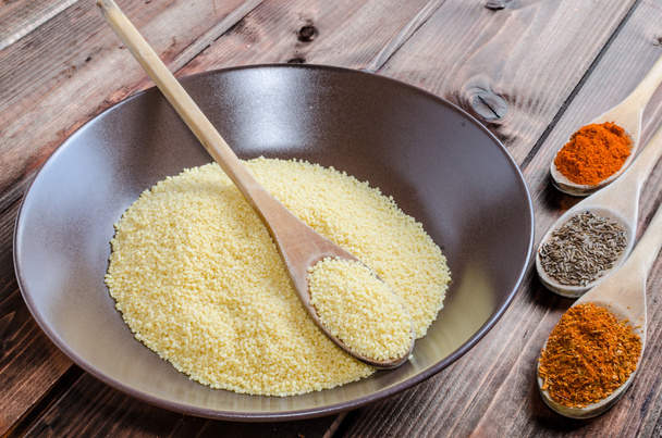 Spice on spoon with bowl of couscous - Foto, afbeelding