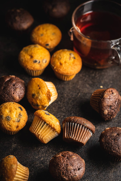 Chocolate and vanilla muffins. Sweet cupcakes on black table. - Fotoğraf, Görsel