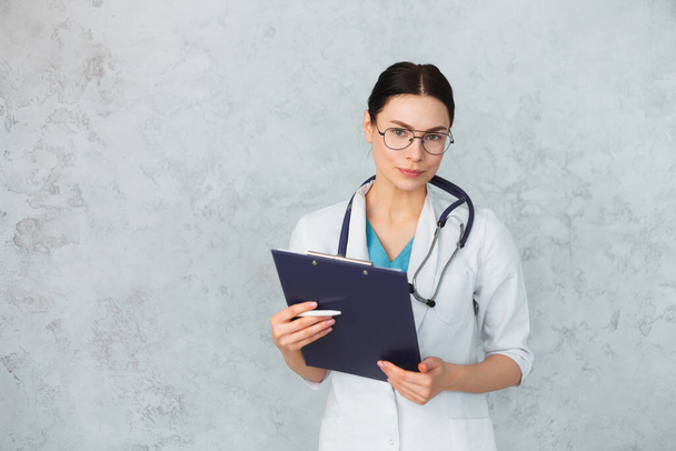 Young female doctor with stethoscope and folder. caucasian brunette. - Foto, imagen