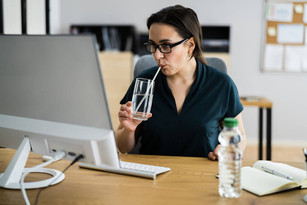 Woman Drinking Water From Glass On Desk While Using Computer - Fotografie, Obrázek