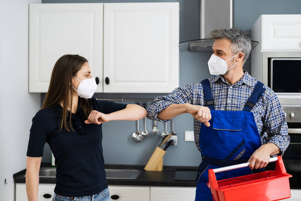 Woman Elbow Bump With Repair Man Or Handyman In Face Mask - Foto, afbeelding