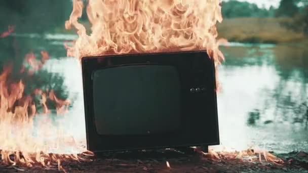 Старый телевизор горит огнем. Позади пруд, который также горит пламенем - Кадры, видео