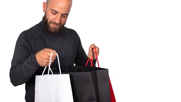 Close-up of young caucasian man looking inside shopping bag. Isolated on white background. Horizontal banner image. Copy space. Shopping concept. Gift concept. - Foto, imagen