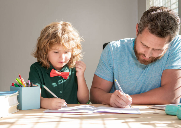 bearded father writing school homework with his kid son in classroom, education - Photo, Image