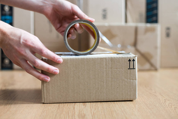 Cardboard box shipping concept: Man is packing a brown parcel - Zdjęcie, obraz