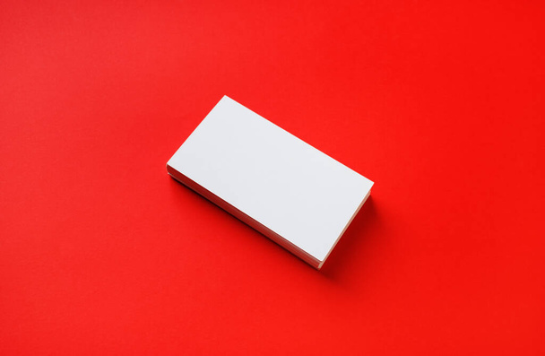 Photo of blank business card on red paper background. Mock-up for branding identity. - Foto, Imagen