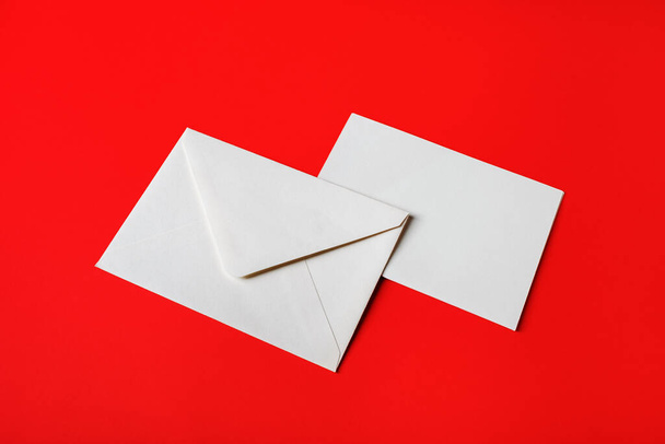 Blank paper envelopes on red paper background. Back and front. Mockup for placing your design. - Foto, afbeelding