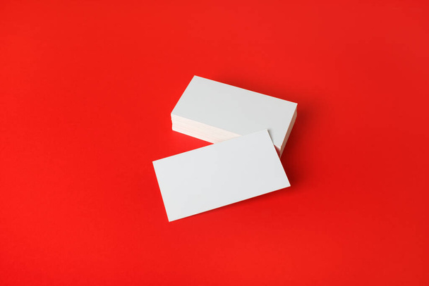 Foto van blanco visitekaartjes op rode papieren achtergrond. Model voor ID. - Foto, afbeelding