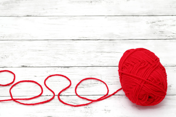 Red ball of wool yarn on a white wooden table - Фото, зображення