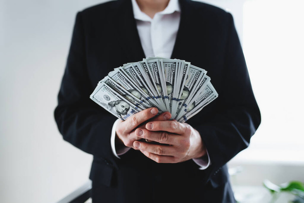 One hundred dollar bills money fun, in hand of man in suit and white shirt. Blurred background. High quality photo - Foto, Imagen