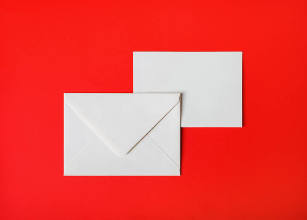 Two blank paper envelopes on red paper background. Back and front. Top view. Flat lay. - Fotografie, Obrázek