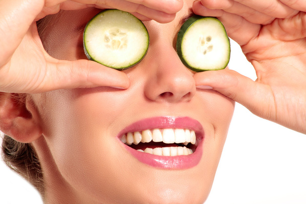 Young beautiflul smiling girl applying a cucumber beauty treatme - Photo, Image