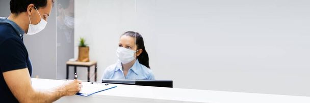 Client Signing Paper At Reception Desk In Face Mask - Фото, изображение