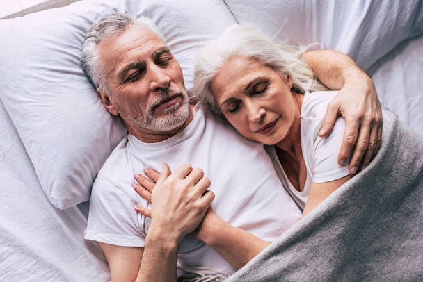 The elderly couple sleeping on the bed - Фото, изображение