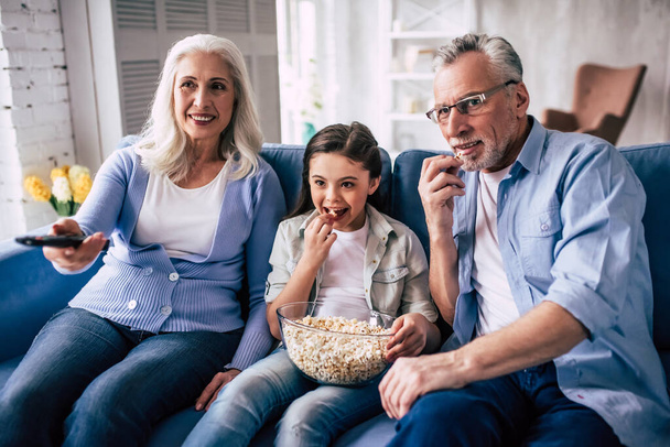 La muchacha feliz y los abuelos de la televisión con una palomita de maíz - Foto, Imagen