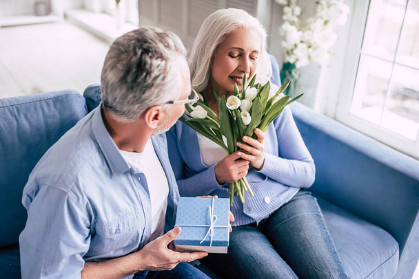 Le vieil homme donnant un cadeau à une femme avec des fleurs - Photo, image