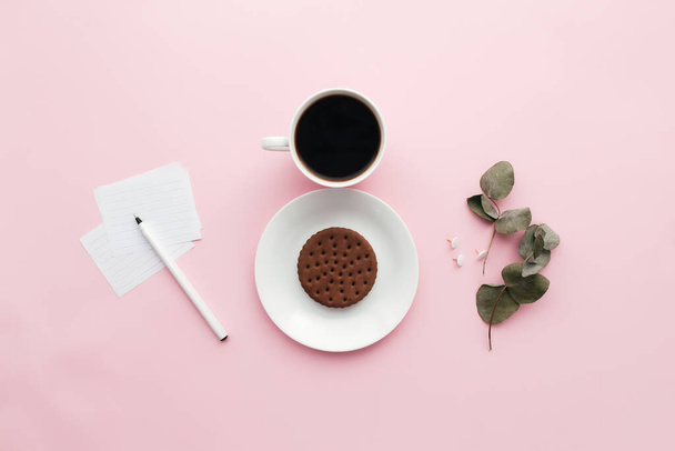 Woman international day concept, coffee cup, plate, cookie, branch, notes, pen, eucalyptus leaves on pink background. High quality photo - 写真・画像