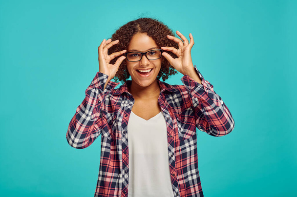Pretty woman in glasses, blue background, positive emotion. Face expression, female person looking on camera in studio, emotional concept, feelings - Fotografie, Obrázek