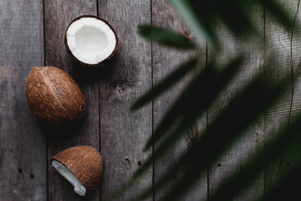 ヤシの葉と灰色の木製の背景に壊れたココナッツ。白いココナッツパルプ。高品質の写真 - 写真・画像