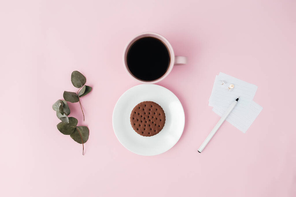 Концепція міжнародного дня жінки, чашка кави, тарілка, печиво, гілка, ноти, ручка, листя евкаліпта на рожевому фоні. Високоякісна фотографія
 - Фото, зображення