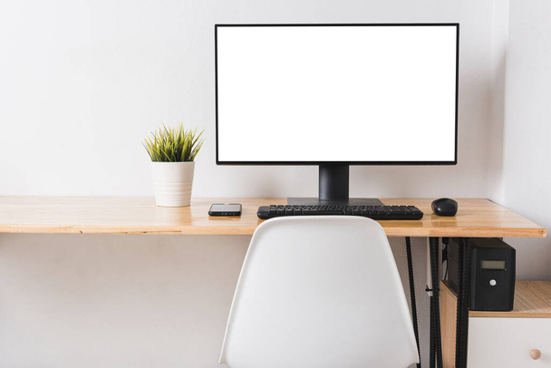 Computer monitor with white blank screen on the business desk with wireless mouse, keyboard at home office over white wall background, Photo of equipment contemporary workspace - Fotoğraf, Görsel