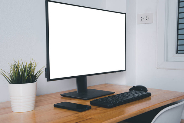 Computer monitor with white blank screen on the business desk with wireless mouse, keyboard at home office over white wall background, Photo of equipment contemporary workspace - Photo, Image