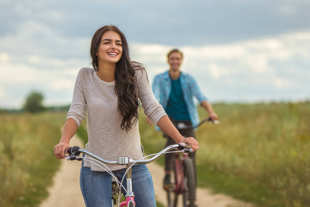幸せな女性は男の屋外近くの自転車に乗って - 写真・画像
