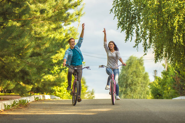 Το ζευγάρι χαμόγελο ιππασία ποδήλατο και χειρονομία εξωτερική - Φωτογραφία, εικόνα