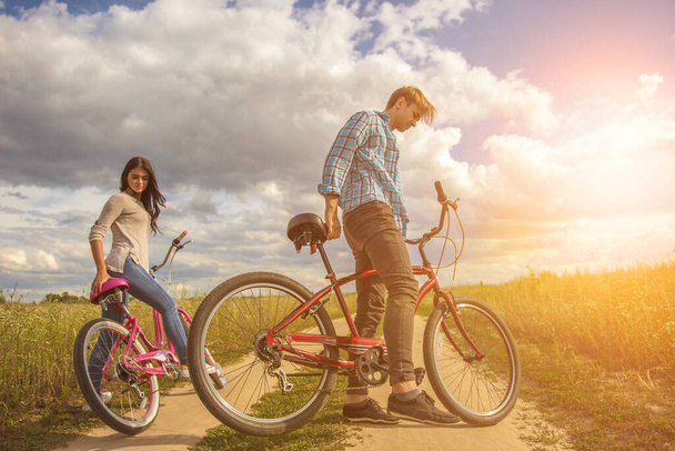 男と女は畑の近くに自転車で立っている。 - 写真・画像