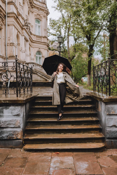 雨の日に傘を持って街を歩く秋の衣装の若いきれいな女性。コピースペース - 写真・画像
