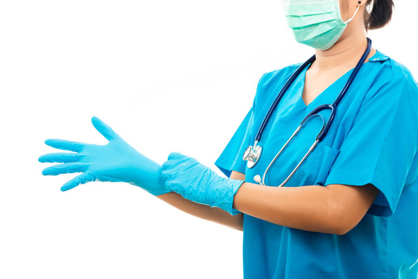 Pielęgniarka stojąca w stetoskopie zakłada gumowe rękawiczki i nosi maskę medyczną, lekarz w niebieskim mundurze, ujęcie studyjne odizolowane na białym tle, koncepcja zdrowia medycznego - Zdjęcie, obraz