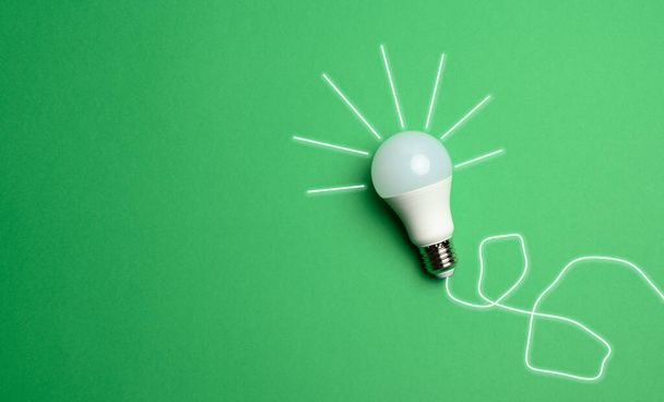 white light bulb with rays on a green background, green energy concept, new ideas, copy space - 写真・画像
