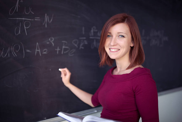 Pretty, young college student writing on the chalkboard, blackboard during a math class - Photo, image
