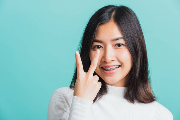 Portrait female give V-sign near-eye make Hollywood white smile, Young beautiful Asian woman showing peace gesture victory, studio shot isolated on a blue background - Fotoğraf, Görsel