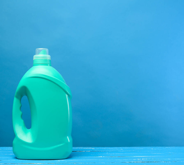 green plastic bottle with detergents on blue background, copy space - Foto, Imagem