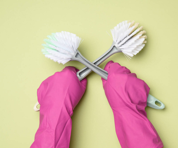 female hand in purple rubber gloves holds a plastic cleaning brush on green background, close up - Фото, зображення