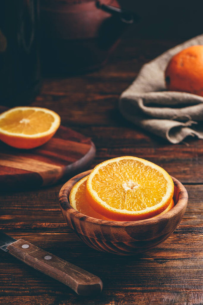 Sliced orange in a wooden bowl in rustic setting - Foto, Bild