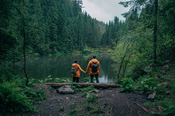 Paar Wanderer in gelbem Regenmantel schaut Bergsee-Backpacker an - Foto, Bild