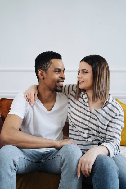 Front view of young diverse couple sitting on a couch at home - Foto, immagini