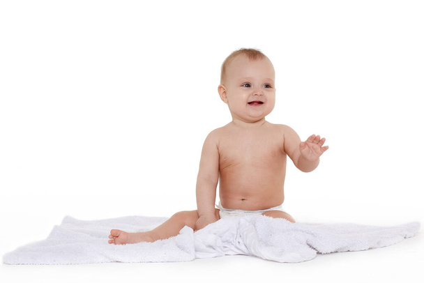 Little baby in diaper is sitting on a plaid on white background and smiling. Eight months - Φωτογραφία, εικόνα