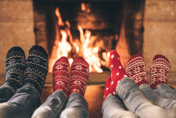 Family in Christmas socks near fireplace. Mother; father and children having fun together. People relaxing at home. Winter holiday Xmas and New Year concept - Foto, Bild
