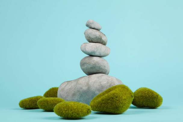 un mucchio di pietre zen in equilibrio circondato da rocce muschiate su uno sfondo estivo turchese. Fotografia di nature morte a colori minima
. - Foto, immagini