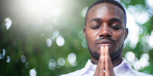 Afričan se modlí za díky Bohu s lehkou světlicí a krásným zadkem v zeleném přírodním pozadí - Fotografie, Obrázek