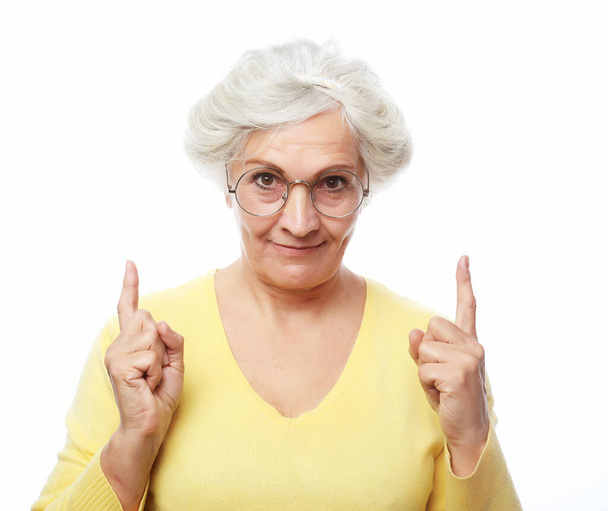 Portrait of a happy senior woman pointing upwards, isolated on a white background - Foto, imagen