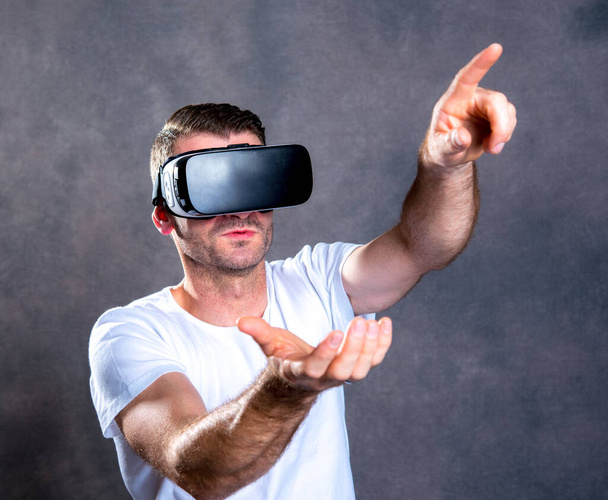 young man with virtual reality glasses pointing upward - Foto, Imagem