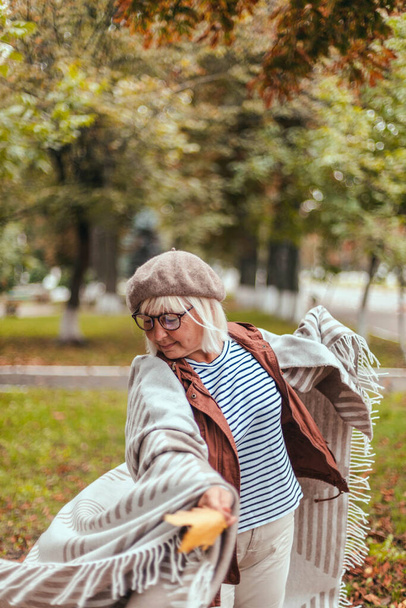 Femme âgée caucasienne en vêtements décontractés chauds et une écharpe confortable s'amuser en plein air profiter de la nature - Photo, image