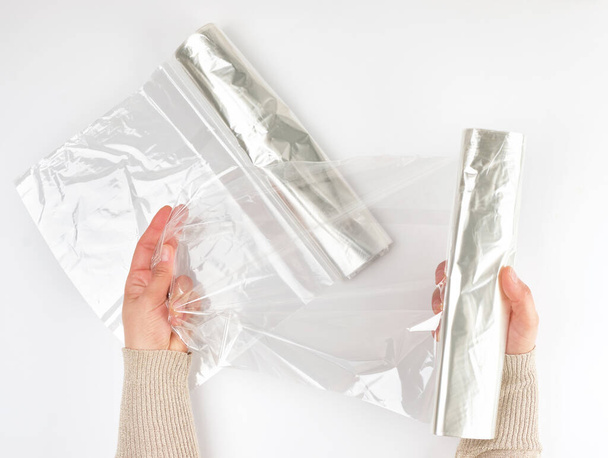 Plastic food wrap for baking products in the oven in women's hand, view from the top, white background - Foto, Imagen
