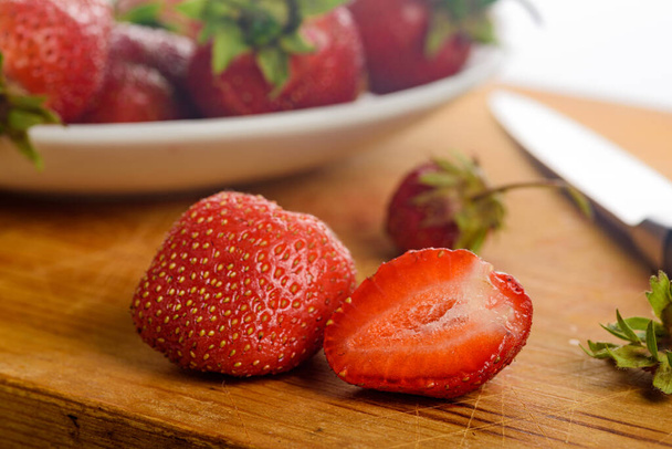 fresh strawberries in a bowl on a wooden table - Foto, afbeelding